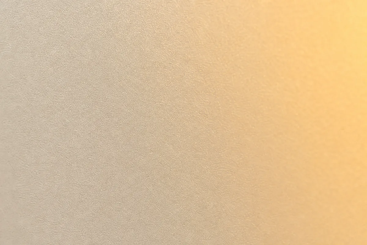 Surface de tôle laquée blanche parcourue par une lumière rasante de fin de journée