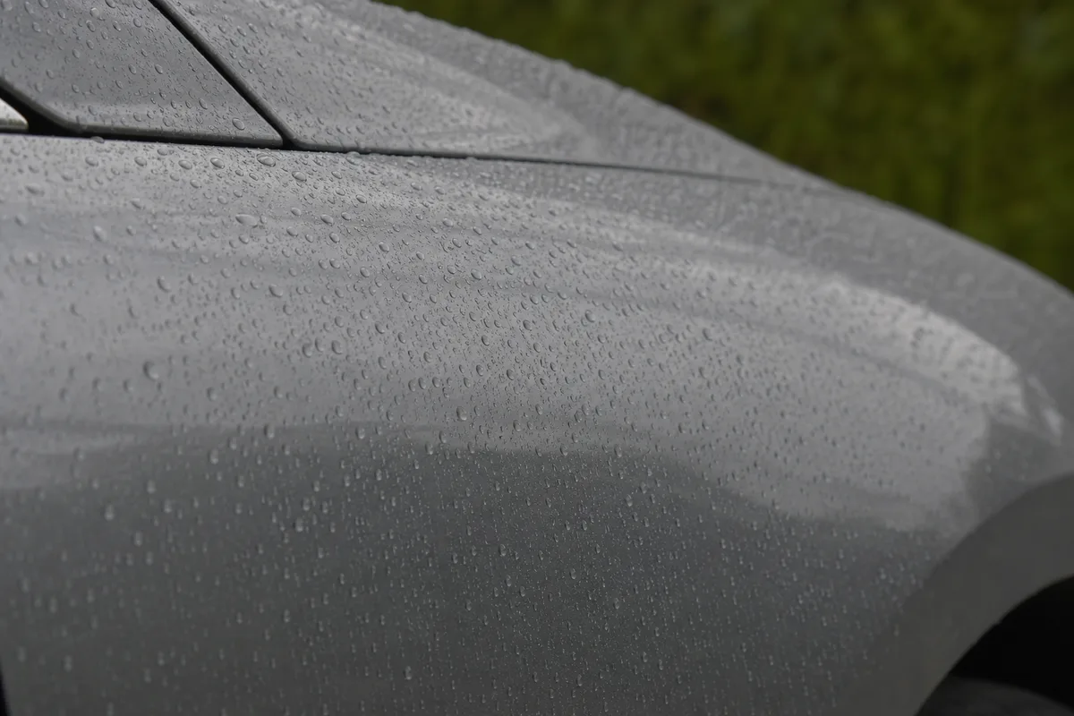 Gros plan sur une aile avant de voiture grise perlée de gouttes d&rsquo;eau après la pluie