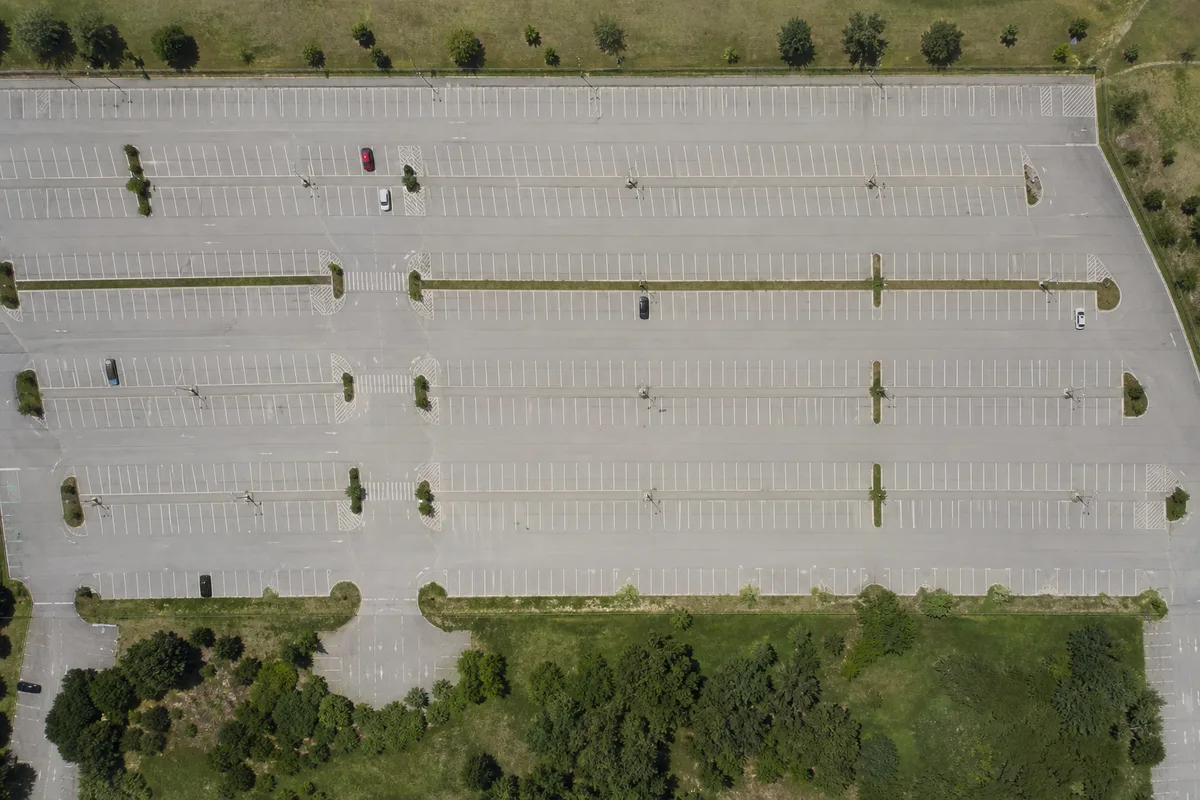 Vue aérienne d’un vaste parking extérieur presque vide en milieu de journée