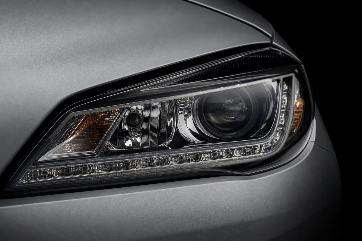 Phare avant d’une voiture moderne en gros plan, optique et diodes détaillées sur une carrosserie grise