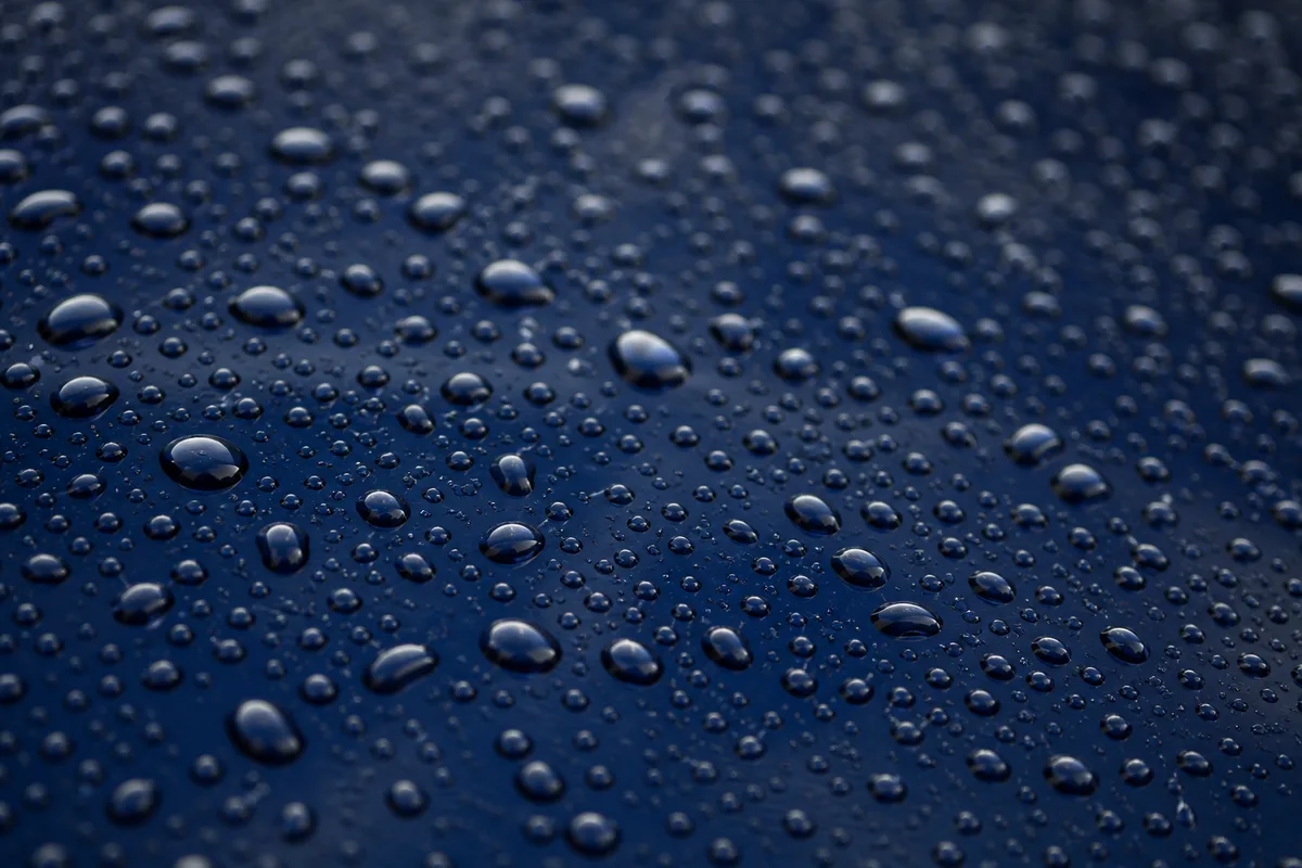 Gouttes de pluie perlées sur une surface de tôle laquée bleu nuit